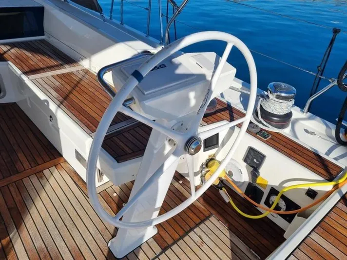 Miss Alice Yacht Photos Pics Steering wheel of a 2018 Beneteau 51.1 yacht with teak deck and blue water backdrop.
