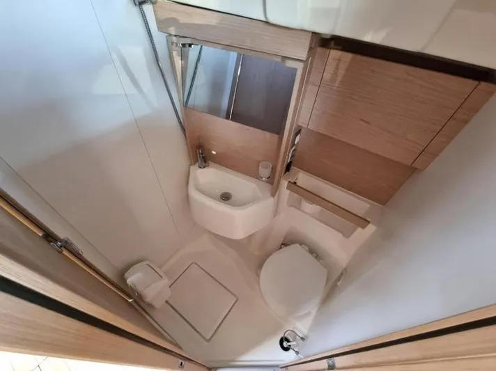 Miss Alice Yacht Photos Pics Compact bathroom in a 2018 Beneteau 51.1 yacht, featuring sink, toilet, and wooden cabinetry.