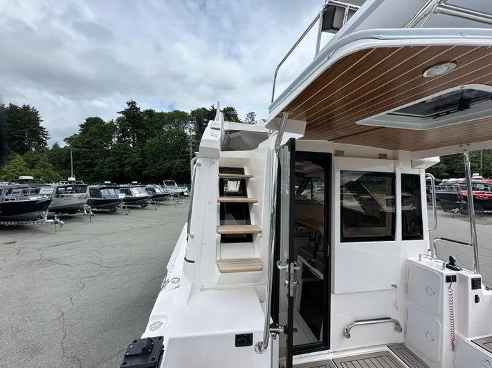  Yacht Photos Pics 2025 Cutwater C-32 CB boat with wooden stairs and open cabin door, parked outdoors.