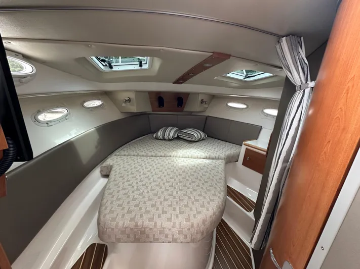  Yacht Photos Pics 2025 Cutwater C-32 CB cabin interior with bed, striped curtains, and wooden accents.