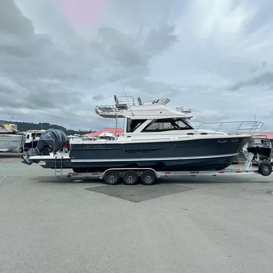  Yacht Photos Pics 2025 Cutwater C-32 CB boat on trailer, parked in marina lot under cloudy sky.