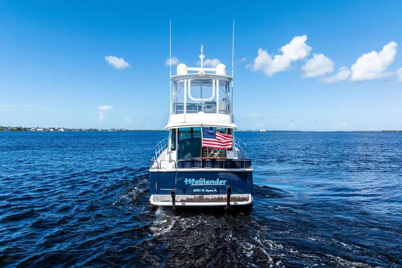 Highlander Yacht Photos Pics 2019 Sabre Flybridge yacht on open water, American flag displayed, clear blue sky.