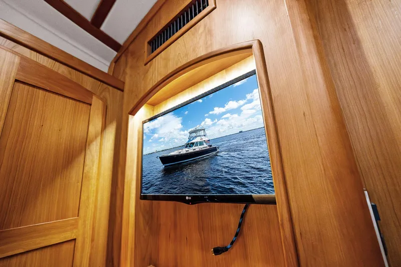 Highlander Yacht Photos Pics Wall-mounted TV displaying a Sabre Flybridge yacht, 2019 model, in a wooden interior.