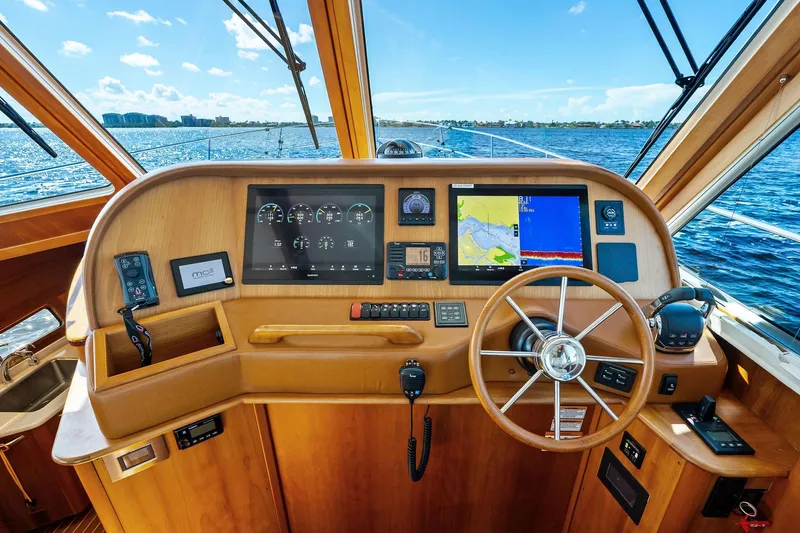 Highlander Yacht Photos Pics 2019 Sabre Flybridge helm with navigation screens, steering wheel, and ocean view.