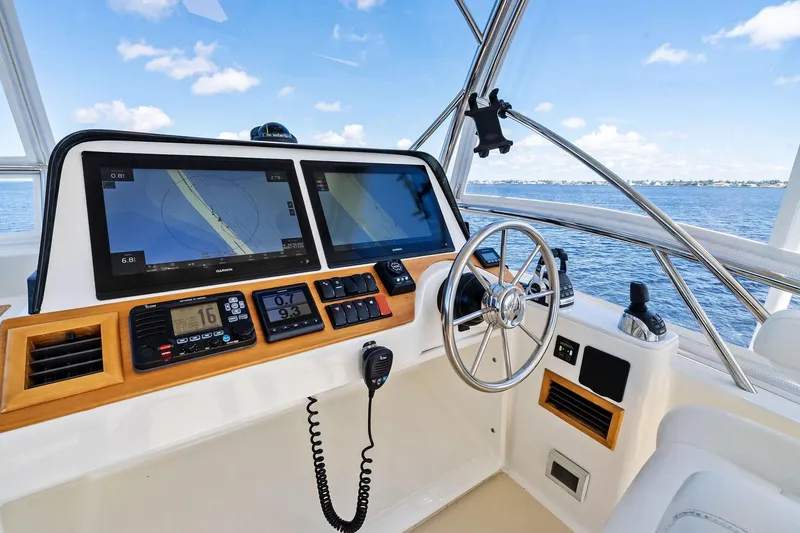 Highlander Yacht Photos Pics 2019 Sabre Flybridge helm with dual navigation screens and steering wheel, overlooking ocean.
