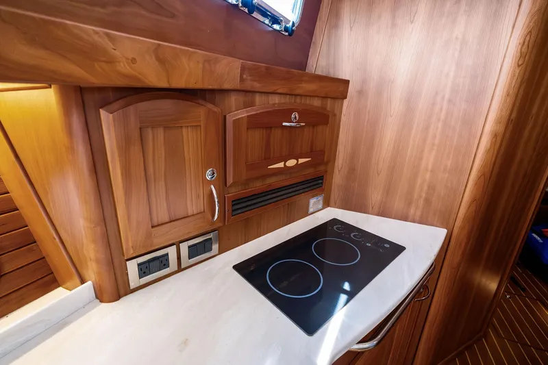 Highlander Yacht Photos Pics 2019 Sabre Flybridge yacht kitchen with wooden cabinetry and modern stovetop.