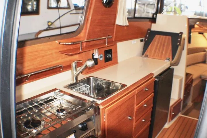 Knot Working Yacht Photos Pics 2020 Ranger Tugs R-27 interior kitchen with wood cabinetry and stainless steel appliances.