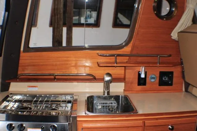 Knot Working Yacht Photos Pics 2020 Ranger Tugs R-27 galley with stove, sink, and wooden cabinetry.