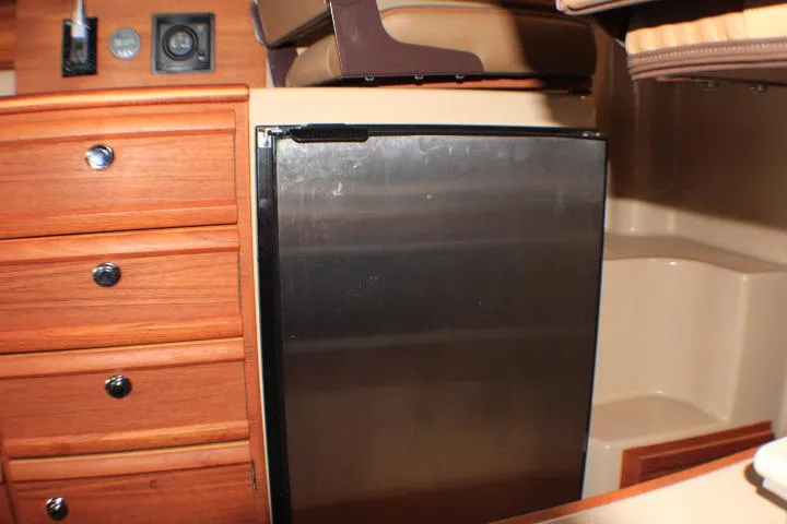 Knot Working Yacht Photos Pics Interior of 2020 Ranger Tugs R-27 featuring a compact stainless steel fridge and wooden cabinetry.
