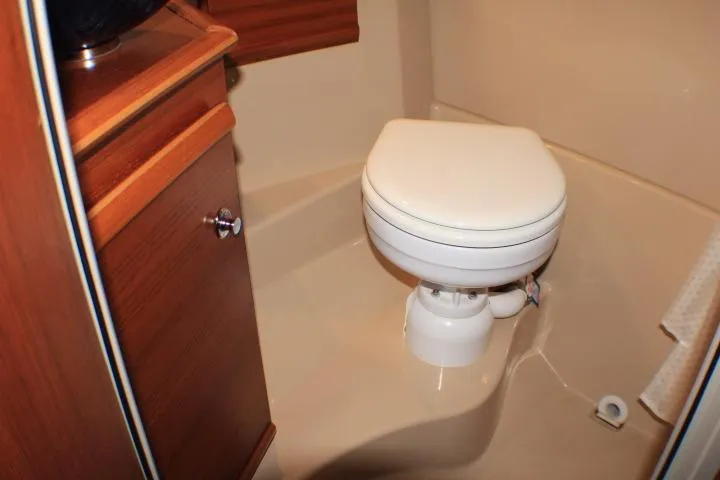 Knot Working Yacht Photos Pics 2020 Ranger Tugs R-27 boat bathroom with compact toilet and wooden cabinetry.