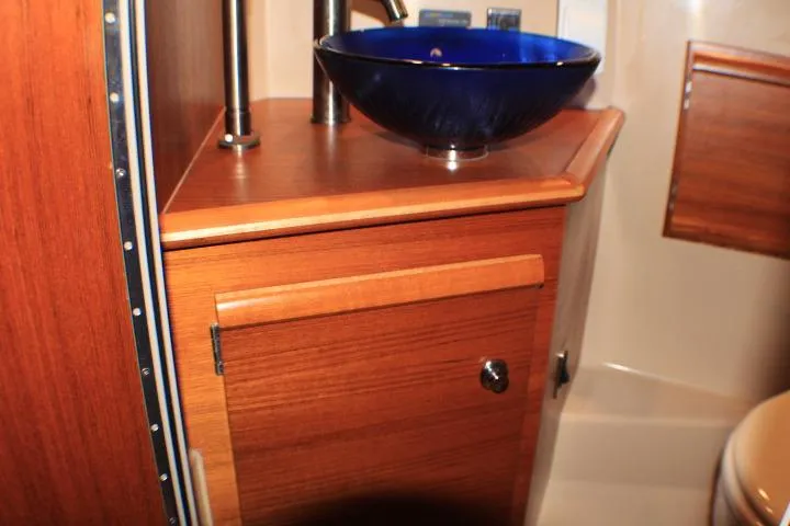 Knot Working Yacht Photos Pics 2020 Ranger Tugs R-27 bathroom with wooden cabinetry and blue glass sink.