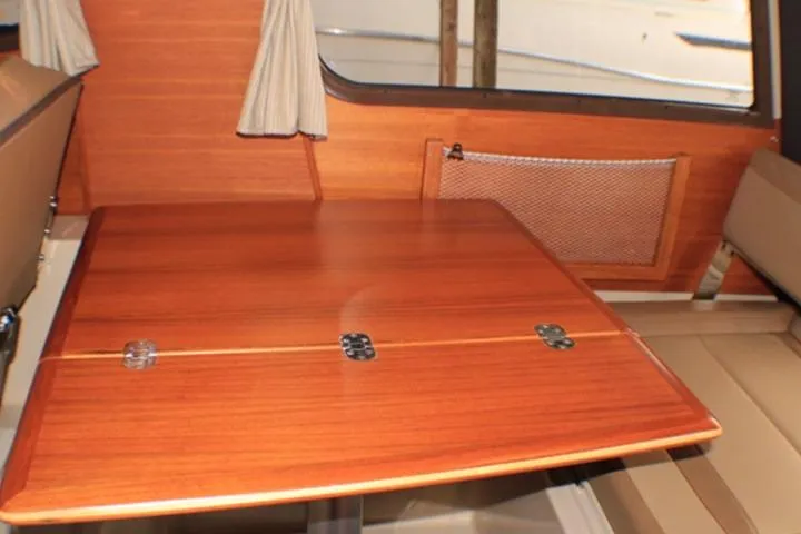 Knot Working Yacht Photos Pics 2020 Ranger Tugs R-27 interior with wooden table and beige seating.
