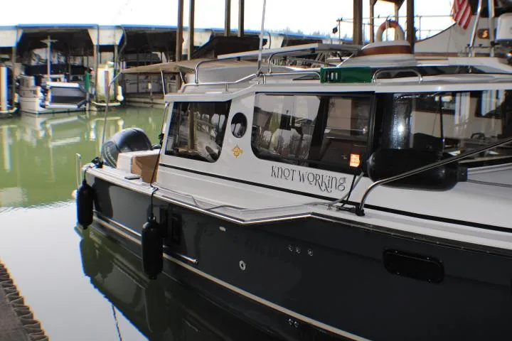 Knot Working Yacht Photos Pics 2020 Ranger Tugs R-27 boat docked in marina, side view with "Knot Working" name.