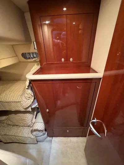 Aqueous Ubiquitous Yacht Photos Pics Interior of 2004 Sea Ray 560 Sedan Bridge with wooden cabinetry and cozy bedding.
