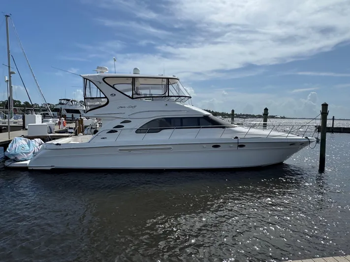 Aqueous Ubiquitous Yacht Photos Pics 2004 Sea Ray 560 Sedan Bridge yacht docked at marina under a partly cloudy sky.
