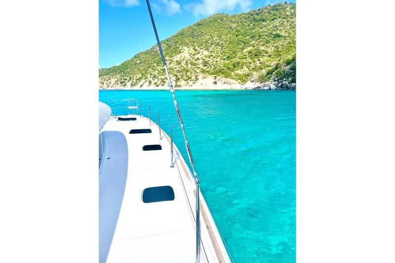  Yacht Photos Pics Lagoon 400 catamaran sailing in clear turquoise waters near a lush green island, 2012 model.