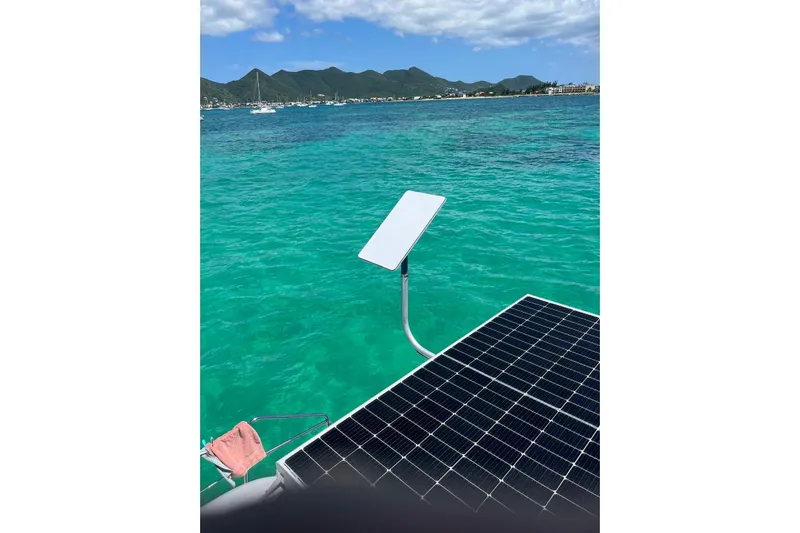  Yacht Photos Pics Lagoon 400 catamaran with solar panel and Starlink, turquoise sea, mountainous coastline.