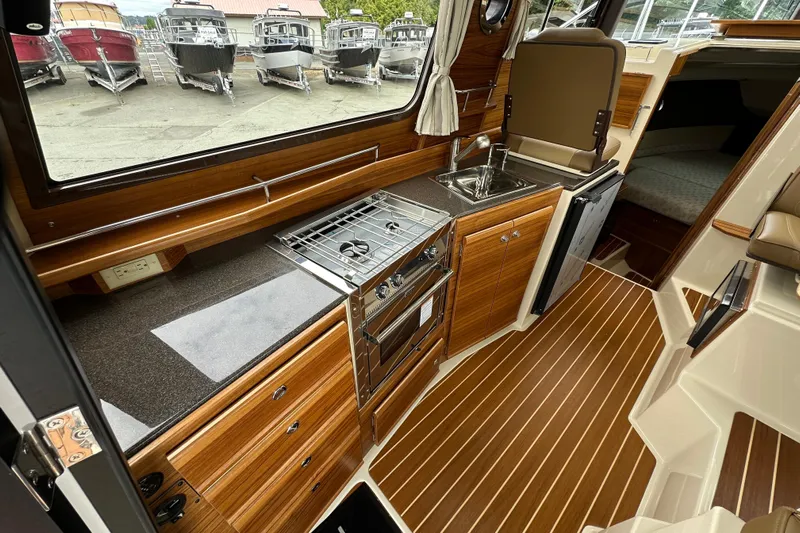  Yacht Photos Pics 2025 Ranger Tugs R-29S interior kitchen with wood cabinetry, stove, and sink.