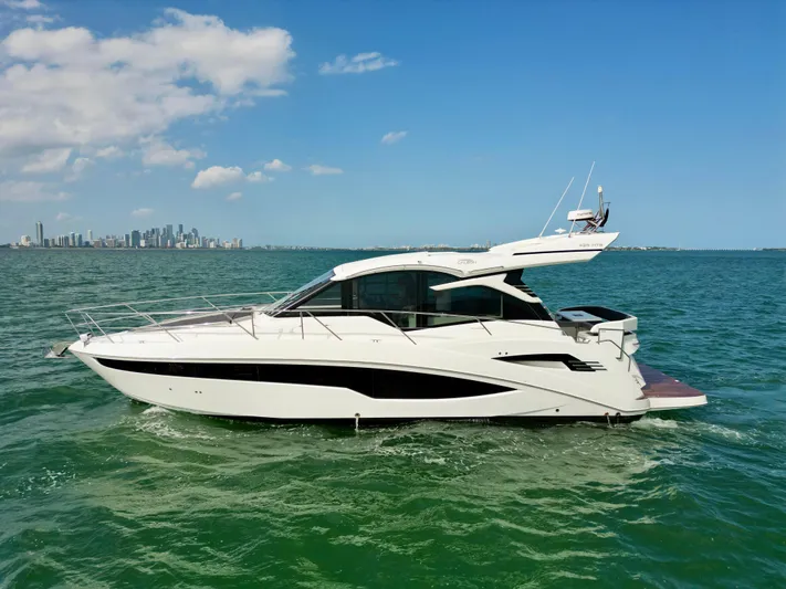  Yacht Photos Pics 2020 Galeon 425 HTS yacht cruising on open water with city skyline in background.
