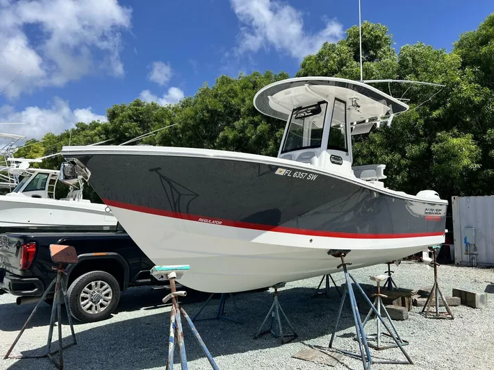T/t Miss Texas Yacht Photos Pics 2020 Regulator 23 boat on stands, gray and white hull, sunny day.