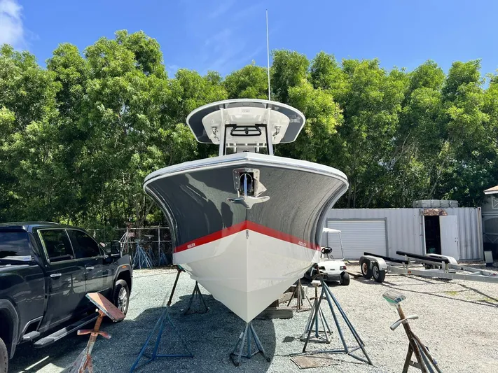 T/t Miss Texas Yacht Photos Pics 2020 Regulator 23 boat on stands, surrounded by trees and vehicles.