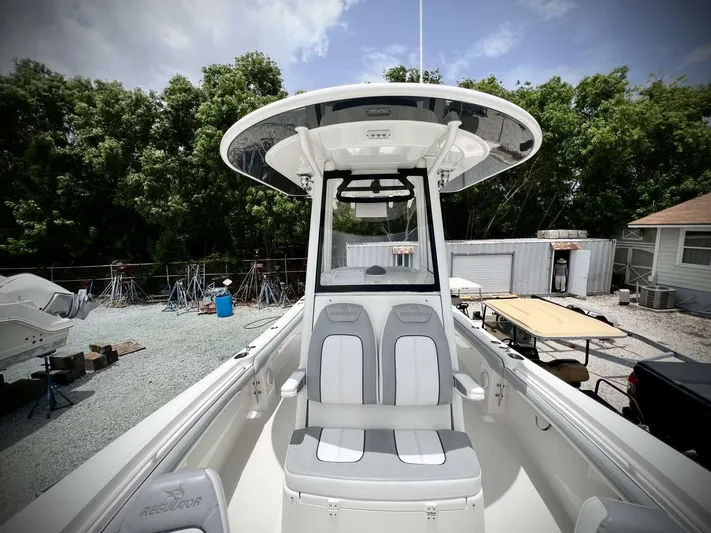 T/t Miss Texas Yacht Photos Pics 2020 Regulator 23 boat with seating, docked outdoors, surrounded by trees and equipment.