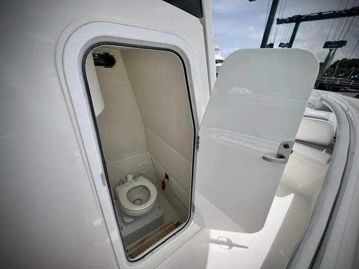 T/t Miss Texas Yacht Photos Pics 2020 Regulator 23 boat interior with open door revealing compact marine toilet.