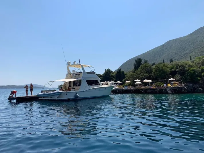  Yacht Photos Pics 1989 Hatteras 58 yacht docked near a scenic coastal area with lush greenery.