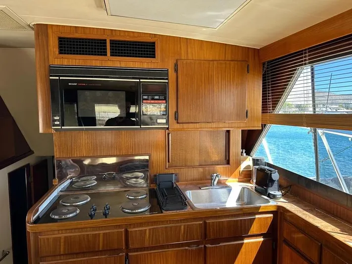  Yacht Photos Pics 1989 Hatteras 58 yacht kitchen with wood cabinetry, stove, sink, and ocean view.