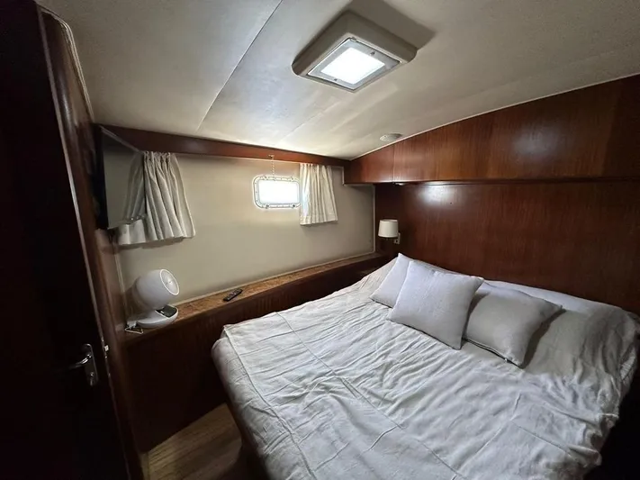  Yacht Photos Pics Cozy bedroom in 1989 Hatteras 58 yacht with wood paneling and natural light.