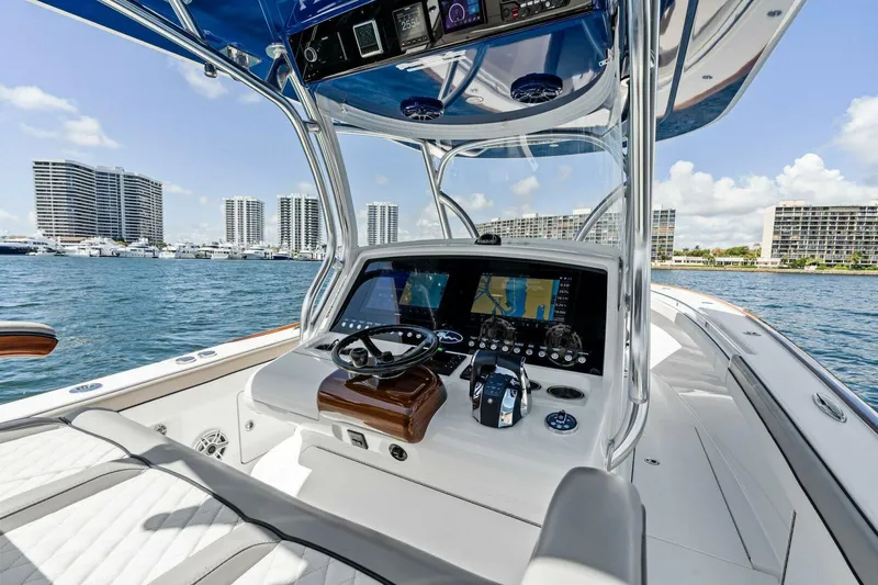 Lily Yacht Photos Pics 2021 Valhalla Boatworks V-33 helm with modern navigation system, cruising near city skyline.