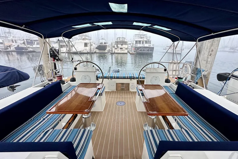 Pain Killer Yacht Photos Pics 2020 Bavaria C50 yacht interior with striped seating, wooden tables, and marina view.