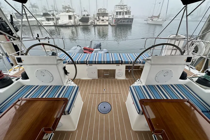 Pain Killer Yacht Photos Pics Cockpit of 2020 Bavaria C50 yacht with striped seating, dual steering wheels, and marina view.