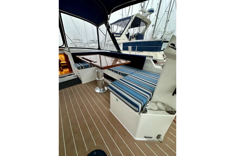 Pain Killer Yacht Photos Pics 2020 Bavaria C50 yacht interior with striped seating and wooden table.