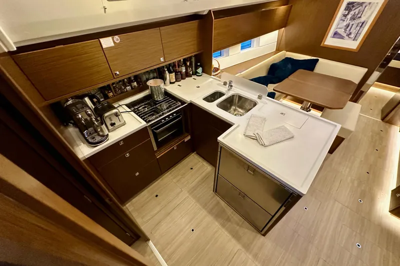 Pain Killer Yacht Photos Pics Modern kitchen interior on a 2020 Bavaria C50 yacht, featuring appliances and dining area.