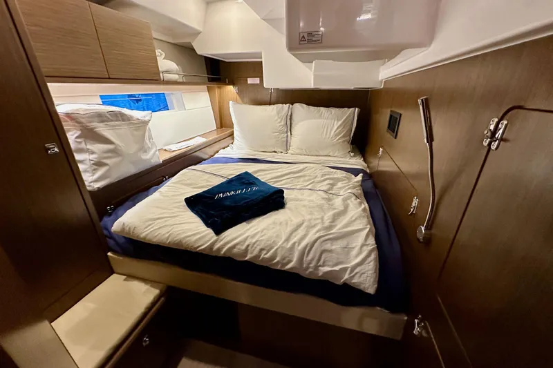 Pain Killer Yacht Photos Pics Cozy cabin interior of 2020 Bavaria C50 yacht with neatly arranged bed and wooden finish.