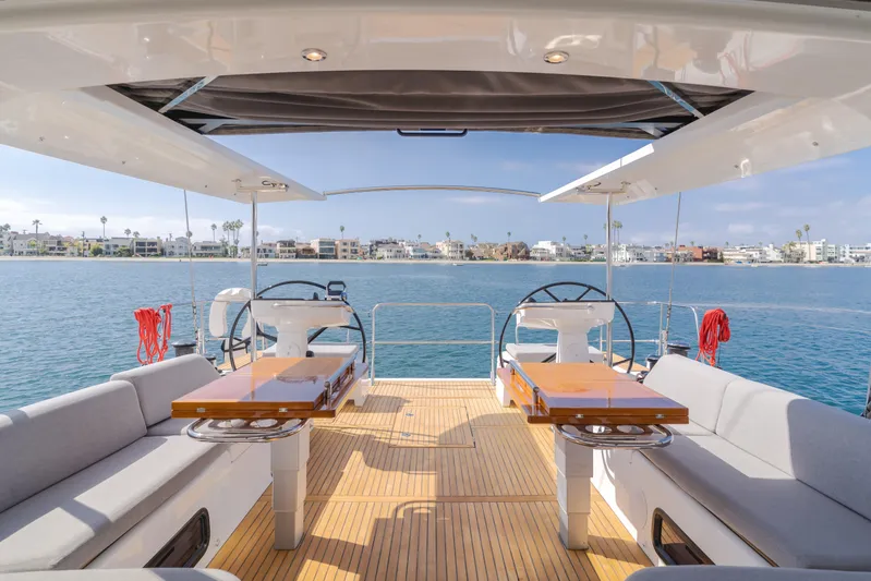 Joy Yacht Photos Pics 2023 Beneteau Oceanis Yacht 60 deck with dual steering wheels and waterfront view.