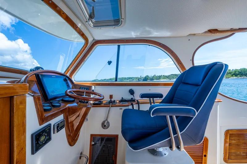 Summer Bliss Yacht Photos Pics Interior of 2001 Hinckley Picnic Boat Classic with blue captain's chair and wooden dashboard.