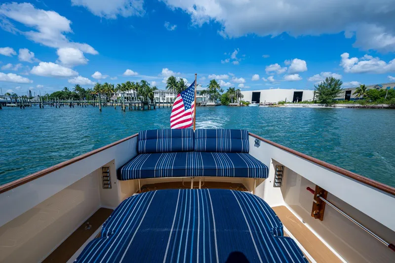 Summer Bliss Yacht Photos Pics 2001 Hinckley Picnic Boat Classic cruising with American flag, blue striped seating, and scenic waterfront.