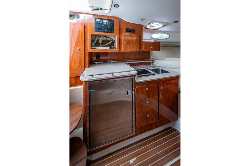  Yacht Photos Pics 2013 Wellcraft 340 Coastal yacht interior with kitchenette, featuring wood cabinetry and stainless steel appliances.