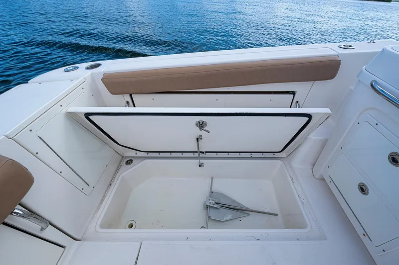 Yacht Photos Pics 2013 Wellcraft 340 Coastal boat with open storage compartment and anchor, on calm water.