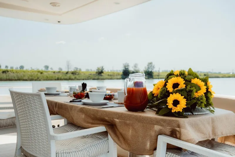  Yacht Photos Pics Outdoor dining setup on 2004 Astondoa 82 GLX yacht with sunflowers and refreshments.