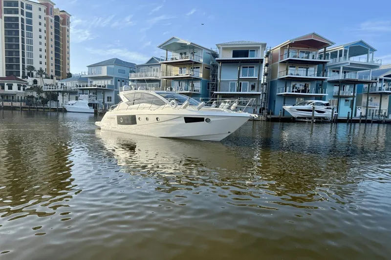 Tom's Cruise Yacht Photos Pics Cranchi M 44 HT 2016 yacht cruising near waterfront homes and high-rise buildings.