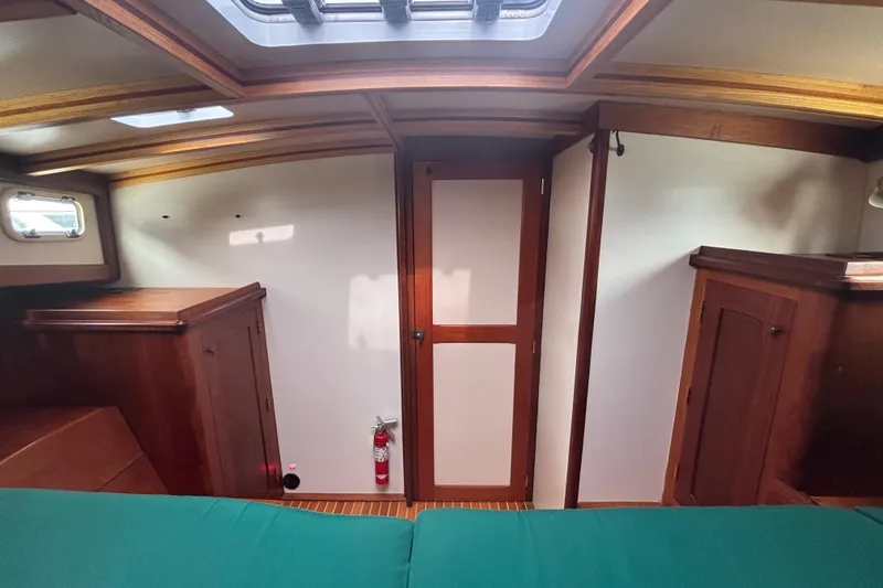 Carroll L Yacht Photos Pics Interior of a 2001 Lowell 40 boat cabin with wooden furnishings and a fire extinguisher.