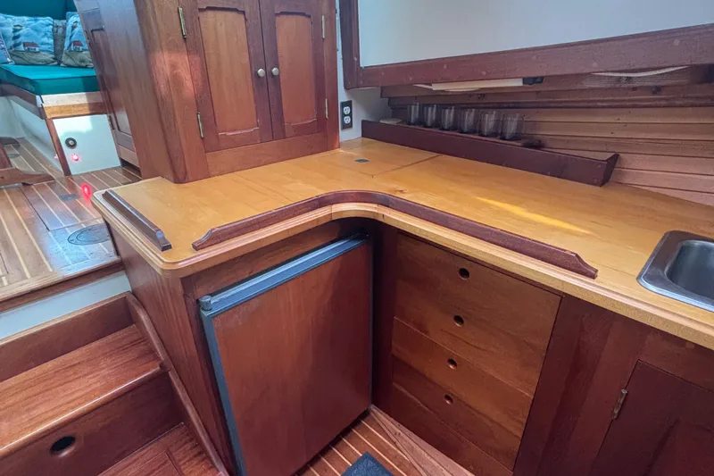 Carroll L Yacht Photos Pics Wooden boat interior with kitchenette, featuring cabinets, mini-fridge, and sink. Lowell 40, 2001 model.