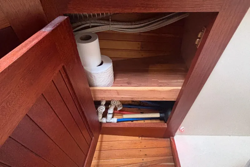 Carroll L Yacht Photos Pics Wooden cabinet interior with plumbing pipes and toilet paper, Lowell 40, 2001 model.