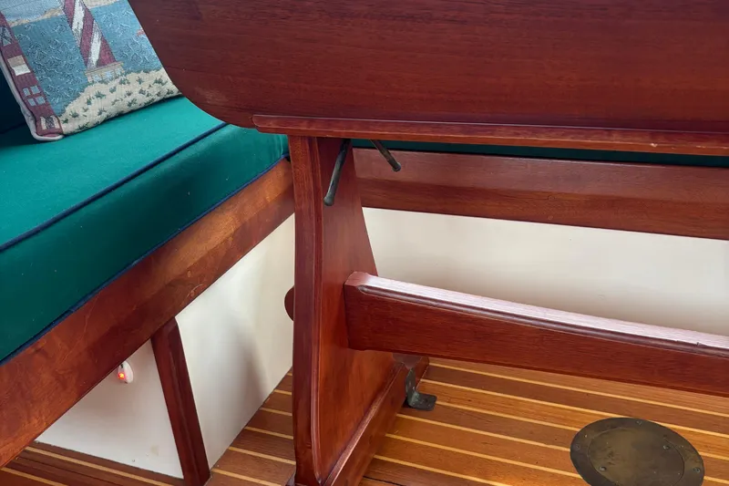 Carroll L Yacht Photos Pics Wooden interior of a Lowell 40 boat, featuring a green cushioned seat and decorative pillow.
