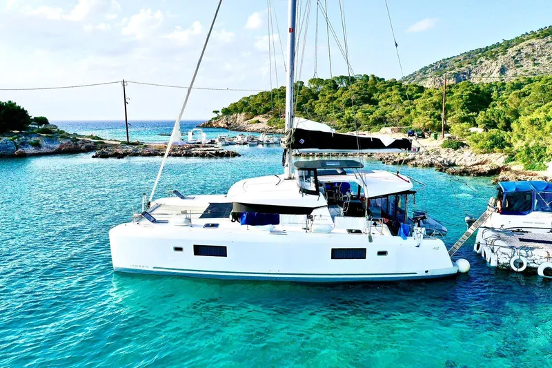Keyma Yacht Photos Pics 2020 Lagoon 42 catamaran anchored in clear turquoise waters near a lush, green island.
