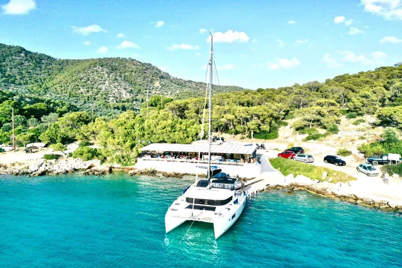 Keyma Yacht Photos Pics 2020 Lagoon 42 catamaran docked by a scenic, lush coastal area.