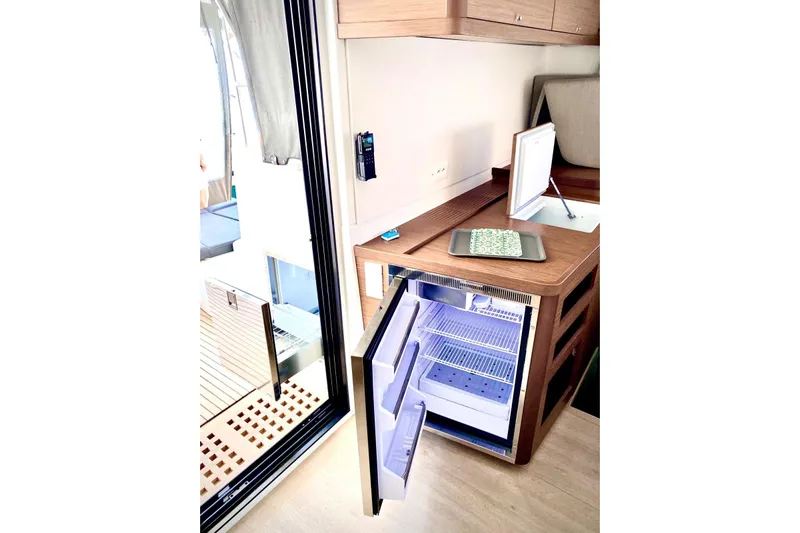 Keyma Yacht Photos Pics Interior of 2020 Lagoon 42 yacht with open fridge and wooden cabinetry.